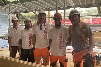 Gruppenfoto STRABAG Mitarbeitende mit Helmen und STRABAG-Shirts