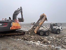 Bild mit einem Baggern und Kipplaster an der Reuss im Nebel