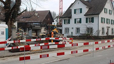 Grütstrasse mit Absperrlatten mit STRABAG Logo in weiss und rot