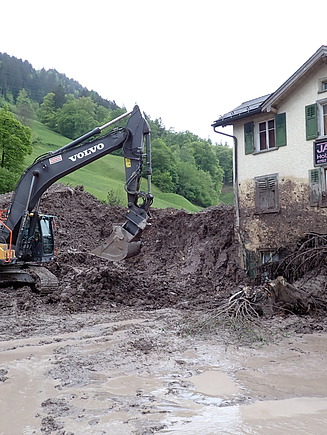 STRABAG-Bagger räumt Schlammmassen von verschüttendem Haus