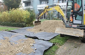 Gelber Bagger beim Verteilen des Erdmaterials