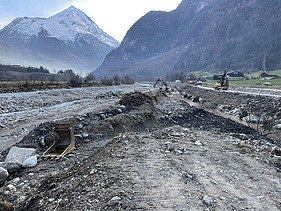 Bild mit zwei Baggern an der Reuss und Bergen im Hintergrund