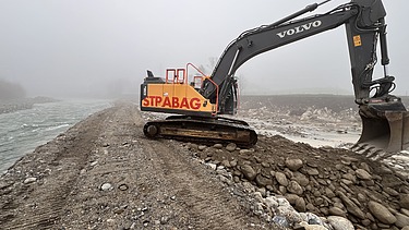 Bild mit einem Baggern und Kipplaster an der Reuss im Nebel